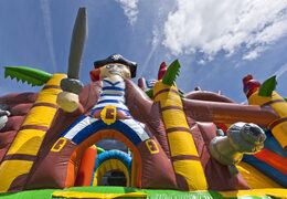 Springkasteel in piratenboot thema met een glijbaan bestellen voor kinderen. Koop opblaasbare springkastelen online bij JB Inflatables Nederland